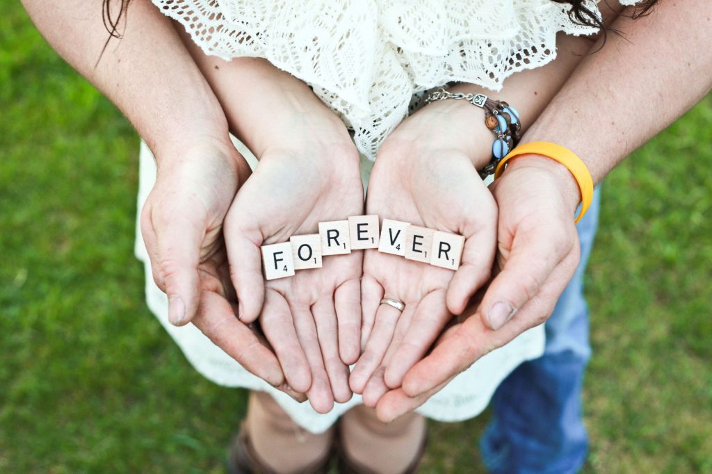 couple holding scrabble pieces that spell out the word 'forever' which is what online couple therapy can help the couple achieve