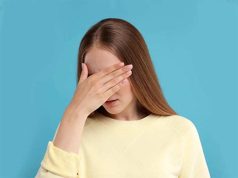 CBT Therapy for shyness showing a woman hiding her face behind her hand